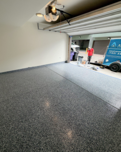 A newly coated garage floor with a worker and Apex Custom Coatings trailer visible in Middleton, WI