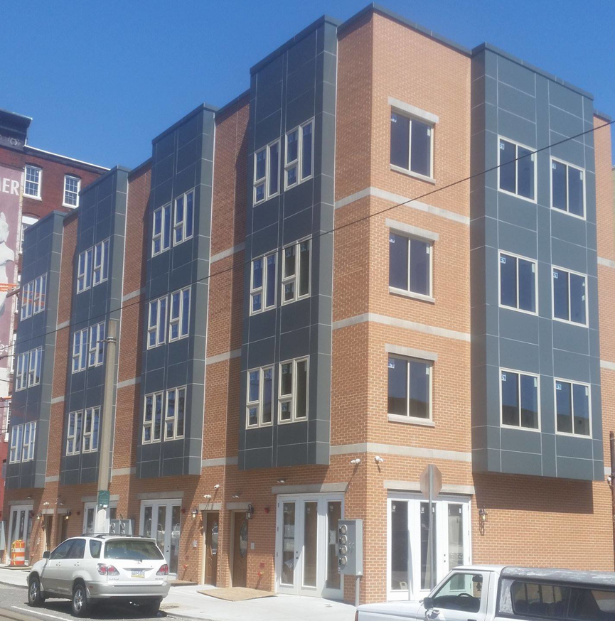 A newly constructed multi-story building with brick and paneling by Just Us Construction Inc in Philadelphia, PA.