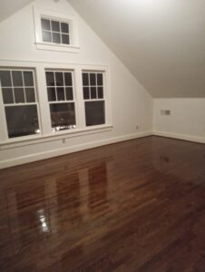 A room showcasing a newly finished and shiny dark hardwood floor by Glenni Floors LLC in Roswell, GA.