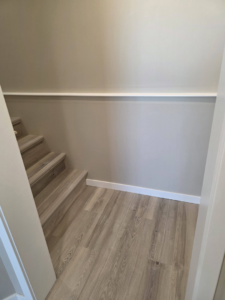 A newly finished staircase with wood-look flooring, baseboard, and chair rail by Rosenthal Remodeling in Milton, WI.