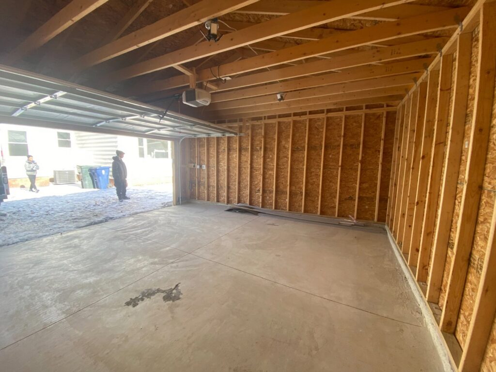 The interior of a newly framed garage with a concrete floor, showcasing construction work by Handy Fix Co. in Cleveland, OH.
