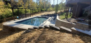 A newly installed backyard pool with surrounding landscaping and retaining walls by Heatwave Pools LLC in Flint, MI.