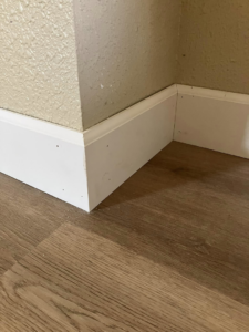 Newly installed white baseboard trim along a wall corner, demonstrating handyman trim work by JMY Construction in Meridian, ID.