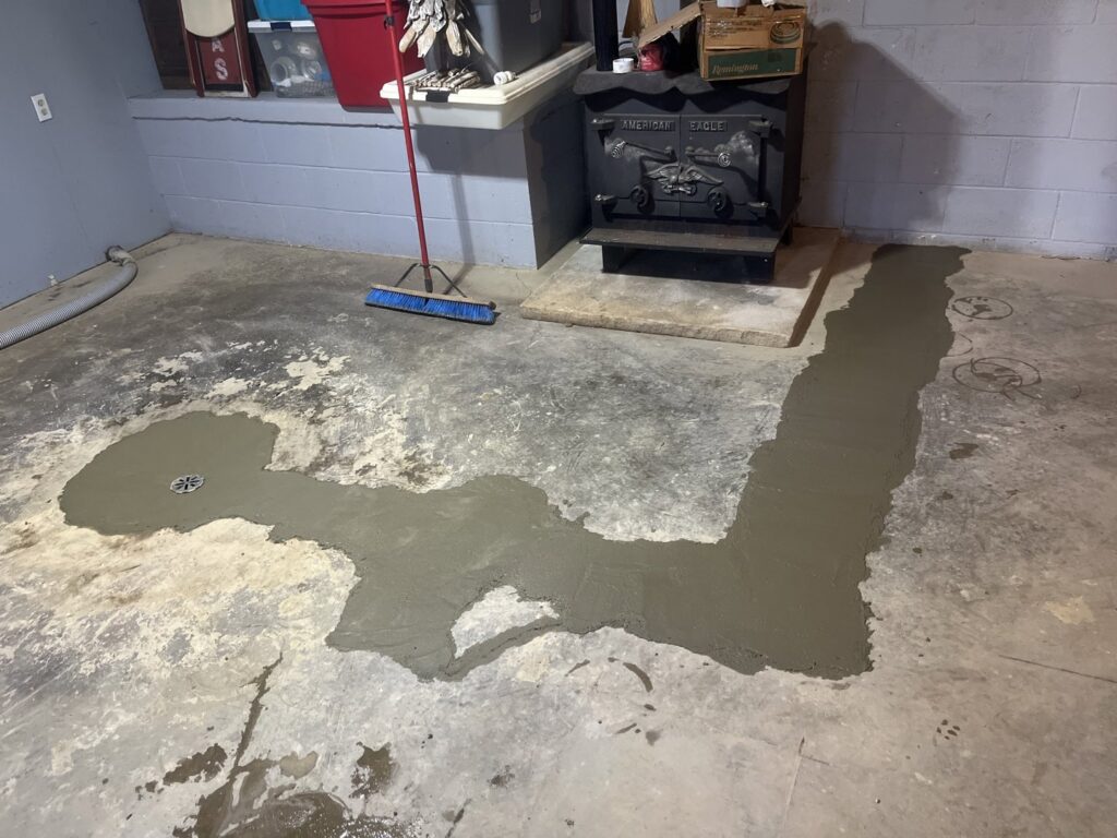 A newly installed interior French drain system with fresh concrete on a basement floor by TCM Waterproofing, LLC in Canton, OH.