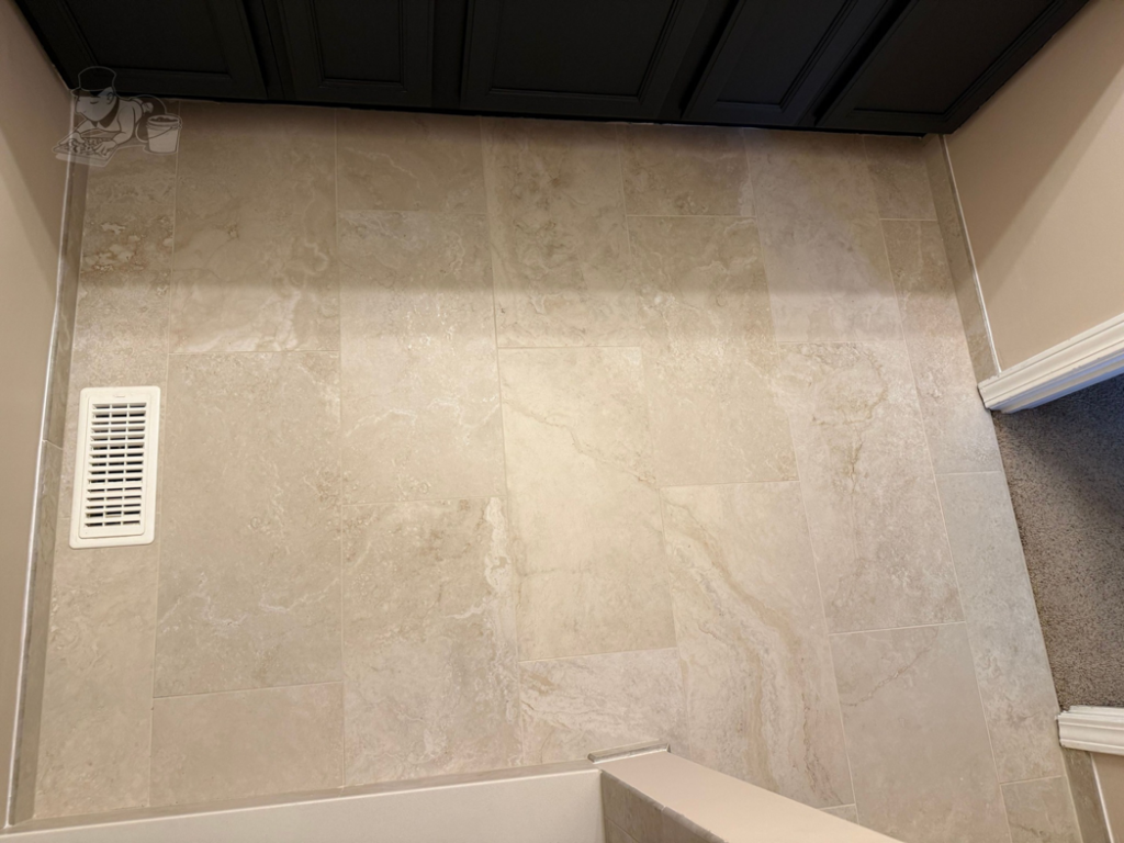 A close-up view of newly installed light-colored rectangular bathroom floor tiles by Artistic Tile & Design in Indianapolis, IN.