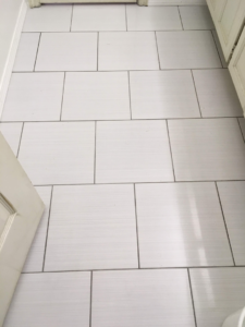 Newly installed white rectangular floor tiles with dark grout in a bathroom by OKC Handyman Services in Oklahoma City, OK.