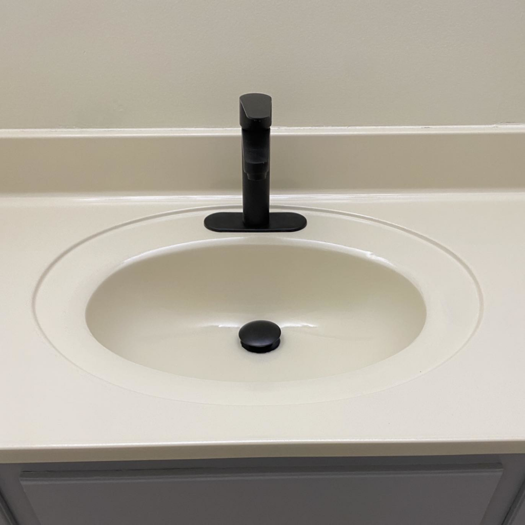 A newly installed modern black faucet and clean white sink in a bathroom, showcasing work by Tupelo Handyman in Tupelo, MS.