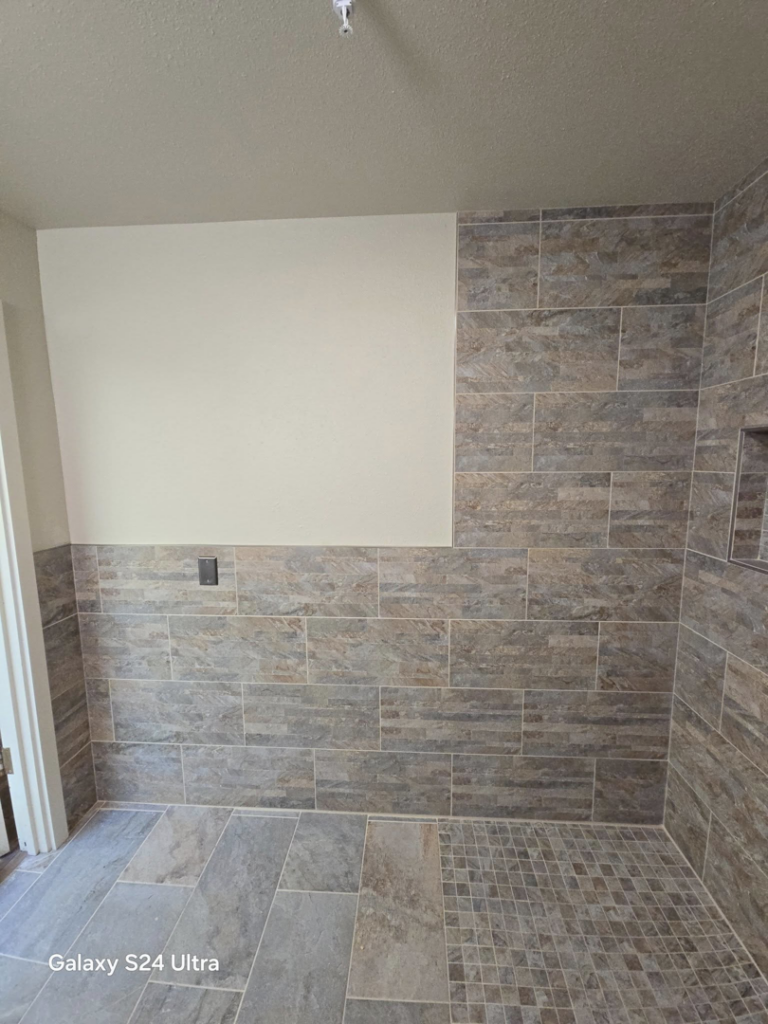 Close-up of newly installed modern grey and brown tiles on the walls and floor of a bathroom by Torres Services in Anchorage, AK.