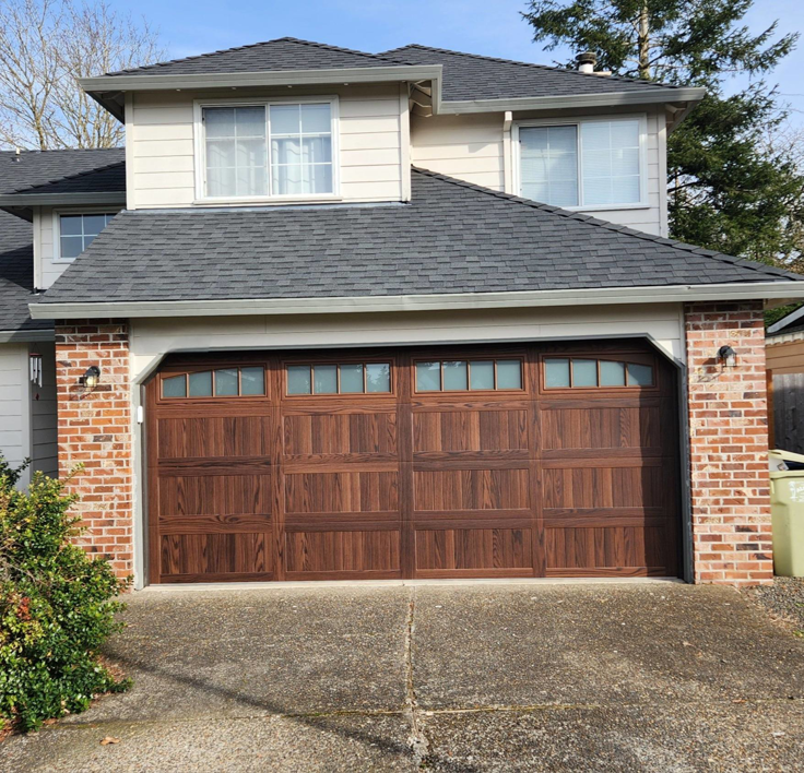A newly installed brown garage door on a house, completed by Pacific Overhead Door in Portland, OR.