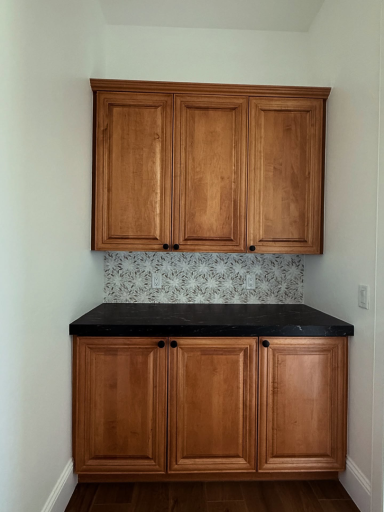 Newly installed wooden cabinets, dark countertop, and decorative tile backsplash by Arcadia Building Company in Mesa, AZ.