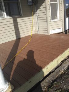 A newly installed composite deck next to a house, completed by Honey Bee's Handyman Services in Hastings, NE.