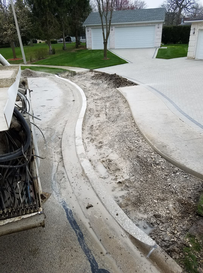 A newly installed concrete curb and disturbed ground, showing general contractor work by National Kurb Kut in Naperville, IL.
