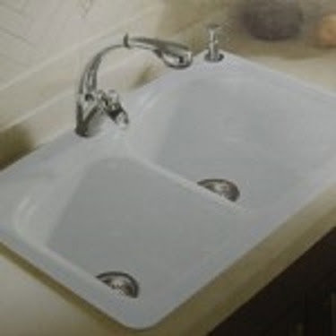 A newly installed white double kitchen sink with a modern faucet by Pocatello Handyman in Pocatello, ID