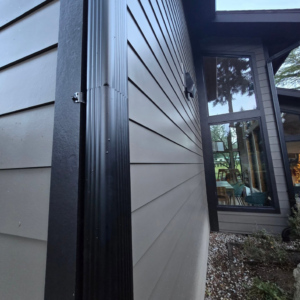 Newly installed black downspout and light-colored siding by Final Touch Construction, LLC in Tukwila, WA