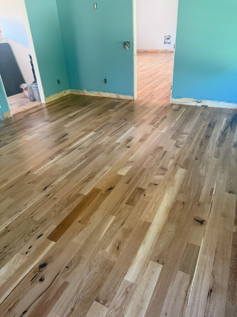 A room featuring newly installed hardwood flooring and blue walls, completed by Cordell Hardwood Flooring in Lexington, KY.