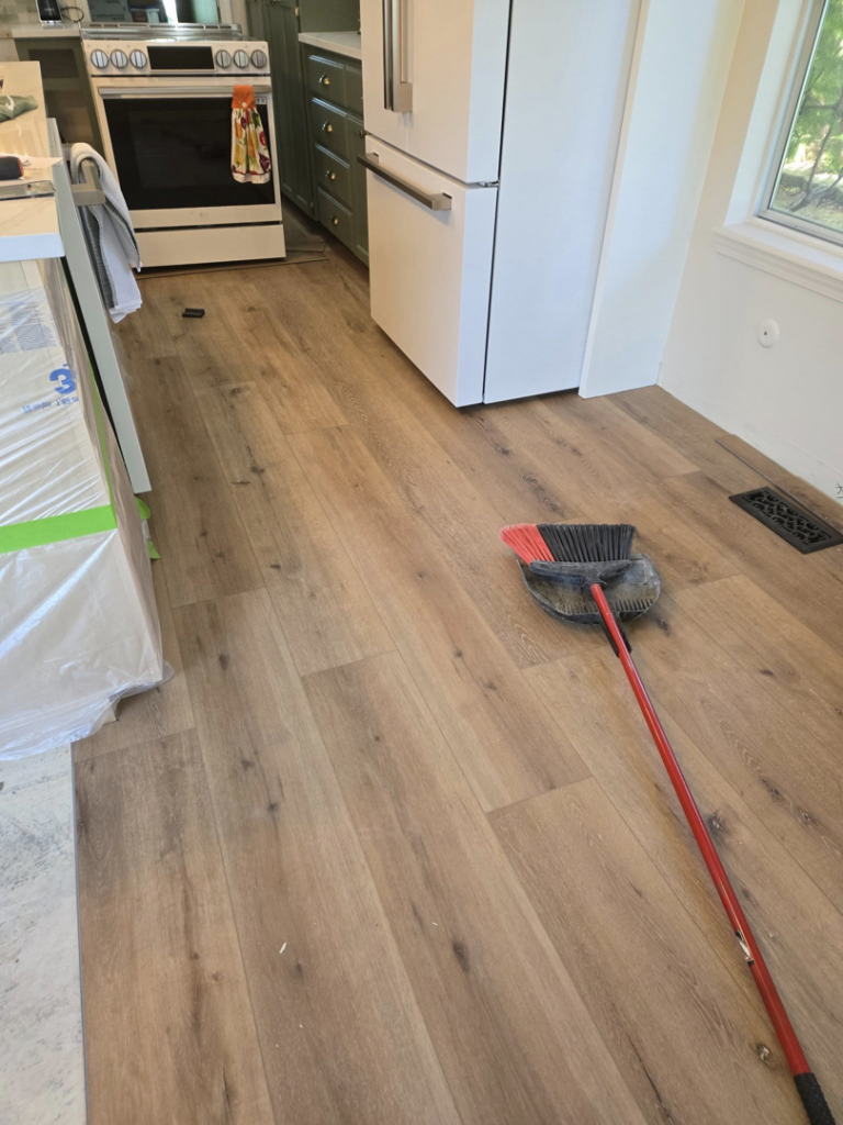 Newly installed kitchen flooring with a broom and dustpan, indicating recent work by Stephen Appel Handyman/Contractor in Meridian, ID.