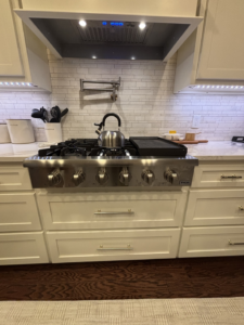 A close-up view of a newly installed kitchen range, pot filler, and subway tile backsplash by Cannon & Associates in Montgomery, AL.
