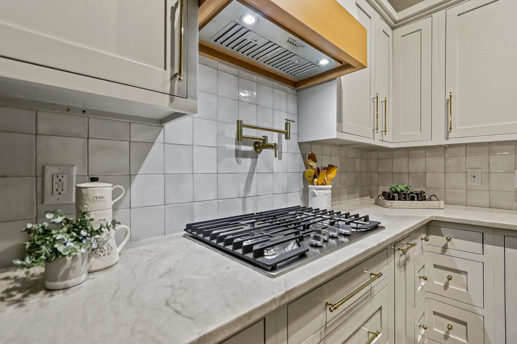 A newly installed kitchen range hood and gas cooktop in a modern kitchen remodel by Innovative Design & Construction in Linwood, KS.