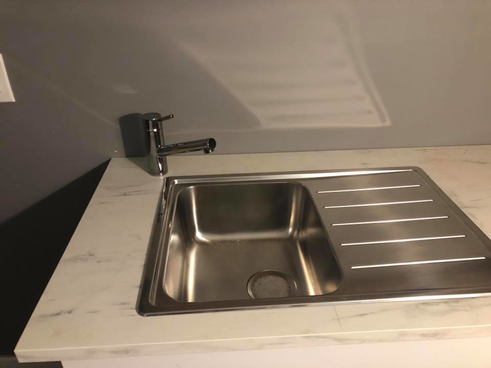 A newly installed kitchen sink and faucet, showcasing quality work by Executive Property Construction at 301 Maple Blvd.