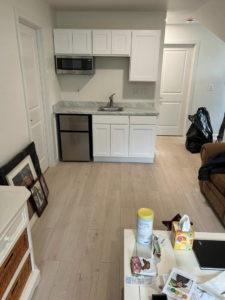 A newly installed kitchenette with white cabinets, sink, microwave, and mini-fridge by G-P Construction in Springfield, OR.
