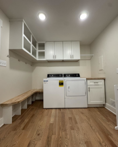 A newly installed laundry room featuring white cabinets, a wooden bench, and appliances by Odd Jobs of Bowling Green in Bowling Green, KY.