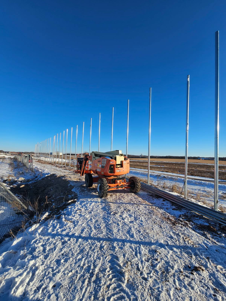 Newly installed metal fence posts stretching into the distance during a fence installation by Fox Valley Fencing LLC in Appleton, WI