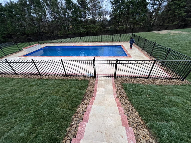A newly installed pool area with black metal fencing and stone steps by Southern Pool Solutions in Knoxville, TN.