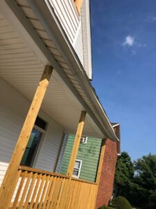 A newly installed porch roof with wooden support columns on the exterior of a house, completed by Home pro handyman llc in Olathe, KS