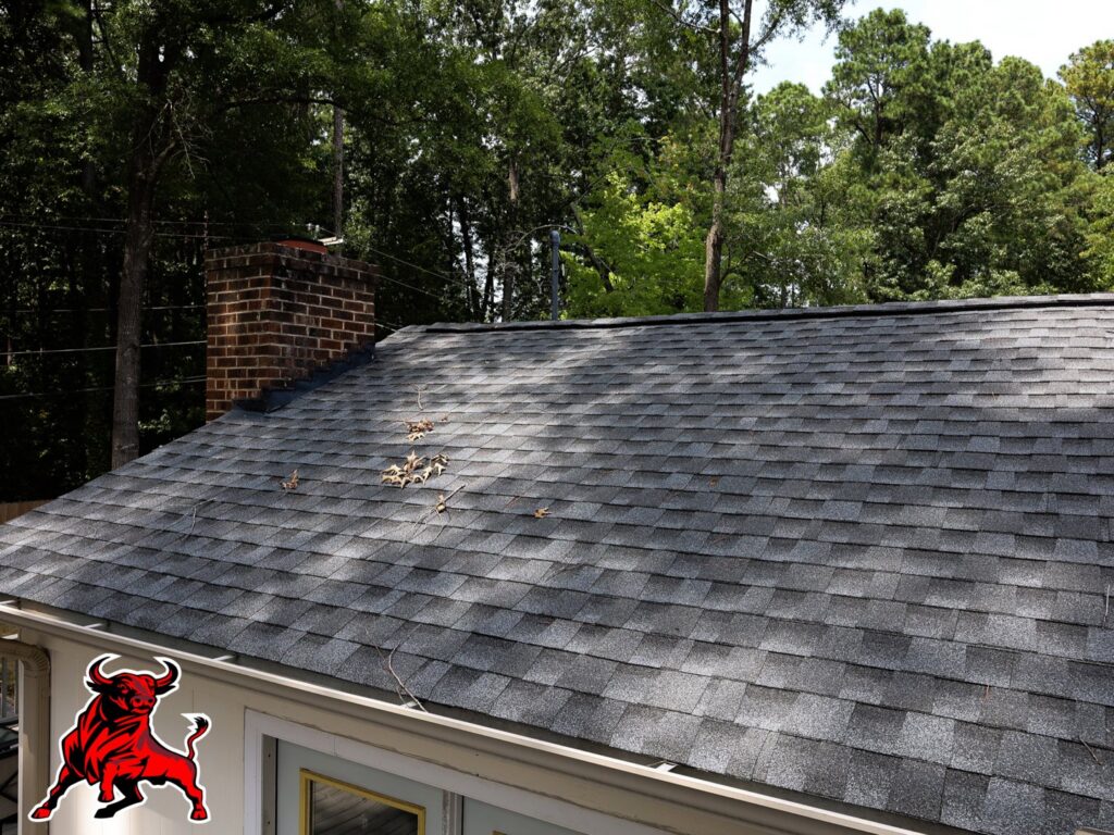 A newly installed roof with dark gray shingles and a brick chimney by Bull City Painting & Roofing in Durham, NC