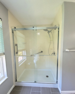 A newly installed shower with clear glass doors and grab bars by Modern Bath, LLC in Knoxville, TN.