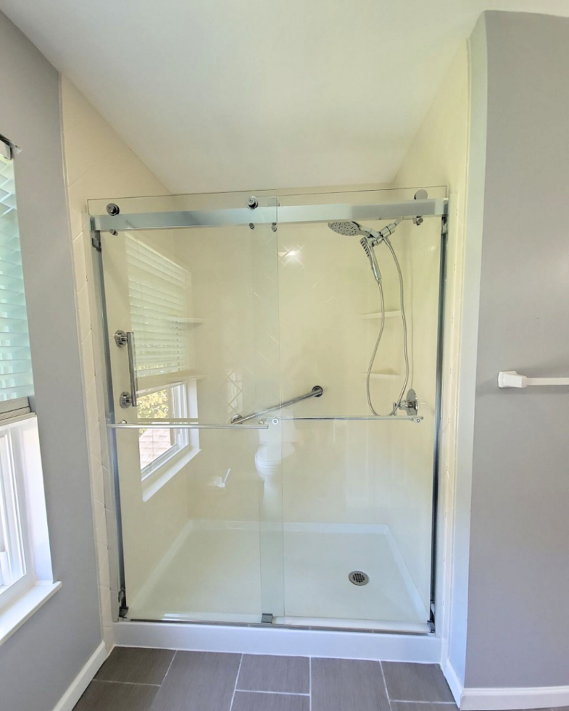 A newly installed shower with clear glass doors and grab bars by Modern Bath, LLC in Knoxville, TN.