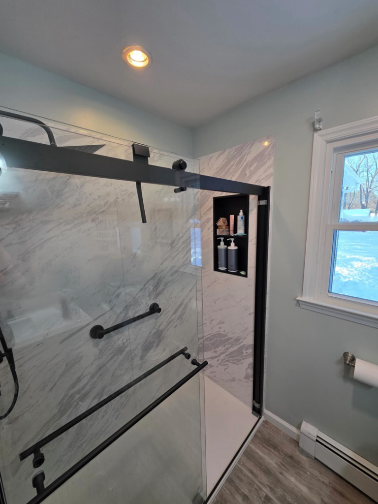 A newly installed shower with modern marble-look tiles and black fixtures by Precision Property Services LLC in South Windsor, CT.