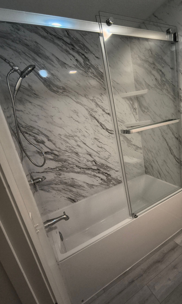A newly installed shower and tub combination with marble-patterned walls by The Shower Company in Kansas City, MO.