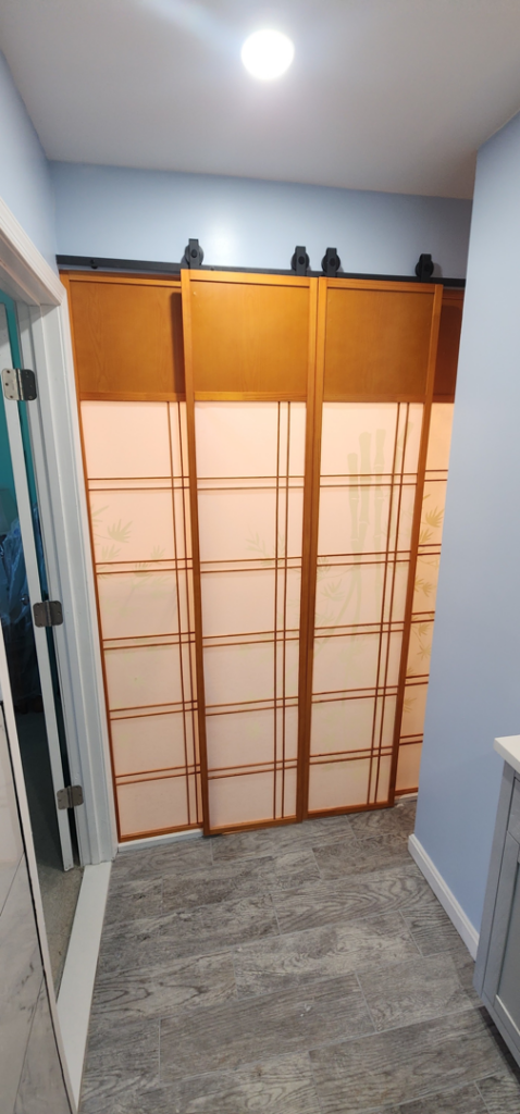 A newly installed modern sliding door with wood and frosted panels by Done Right Construction in Johnston, IA.