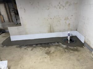 Newly installed sump pump and concrete patch covering interior drainage system by Pioneer Basement Solutions in Canton, OH.