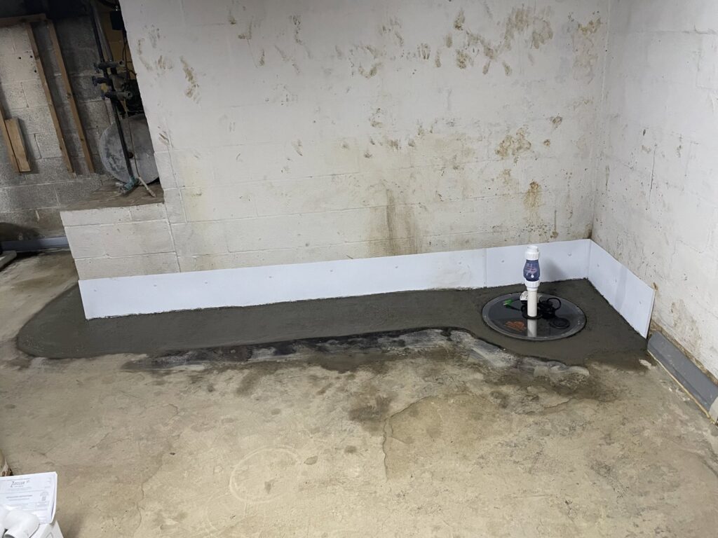 Newly installed sump pump and concrete patch covering interior drainage system by Pioneer Basement Solutions in Canton, OH.