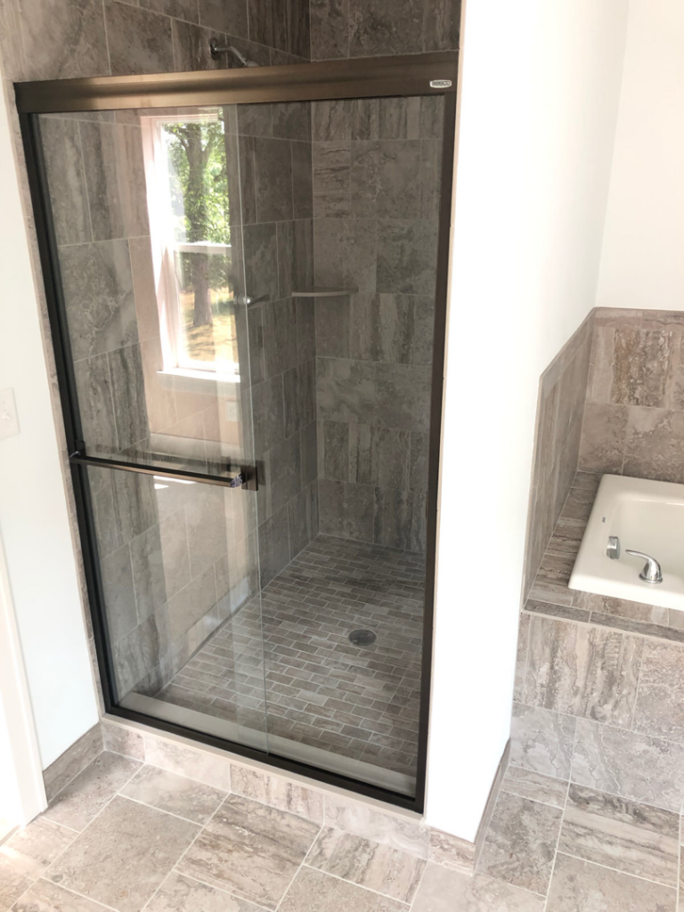 A newly installed tiled shower and glass door from a bathroom remodel by Handyman Helper in Simi Valley, CA.