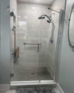 A newly installed walk-in shower with modern grey tiles and a glass door by Artistic Tile & Design in Indianapolis, IN.
