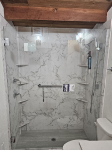 A newly installed walk-in shower with marble-patterned walls and glass doors, completed by Prestige Statewide, LLC in Eugene, OR.