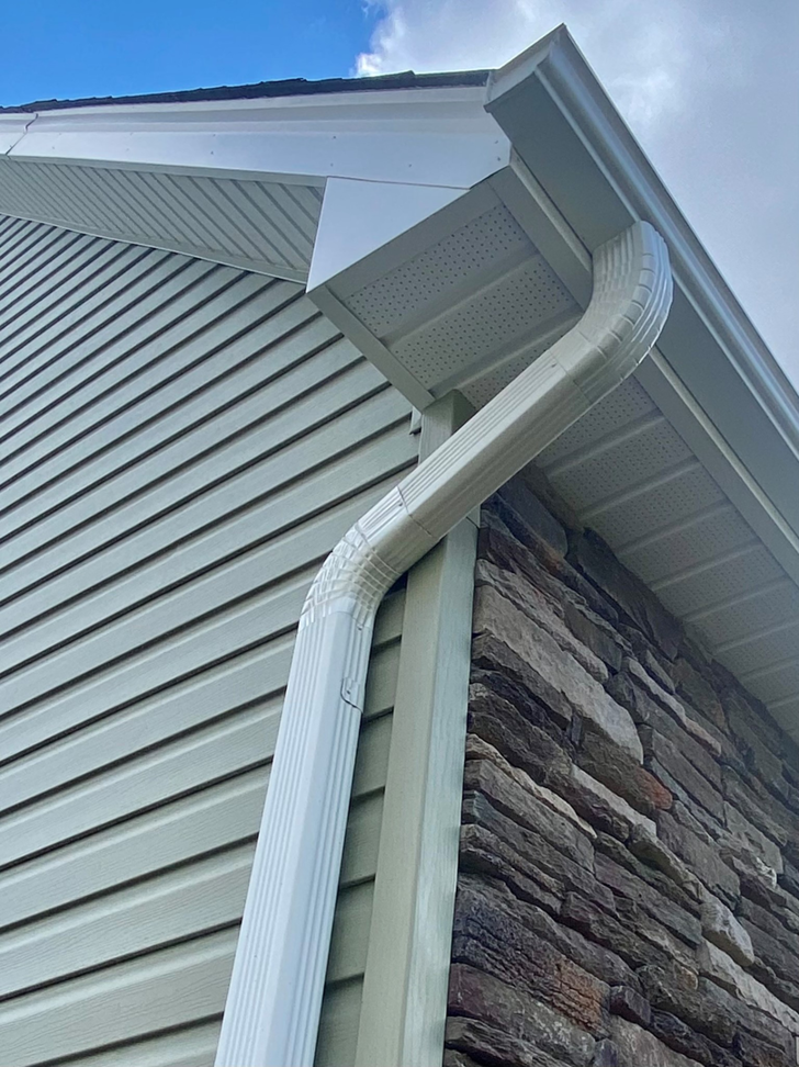 Newly installed white gutter and downspout on a house, demonstrating quality work by Monroe Gutter Pros in Charlotte, NC.