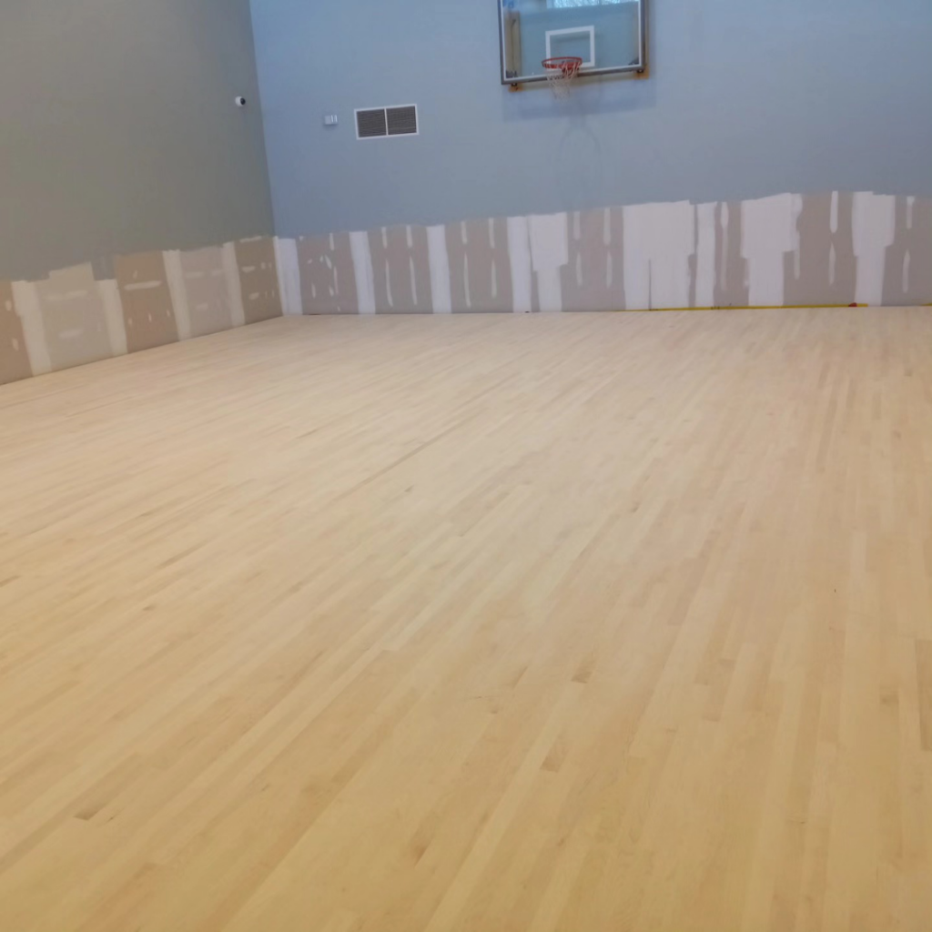 A newly installed light-colored wood floor in a large gym or court by Robert C. Mihaich Wood Flooring in Worcester, MA.