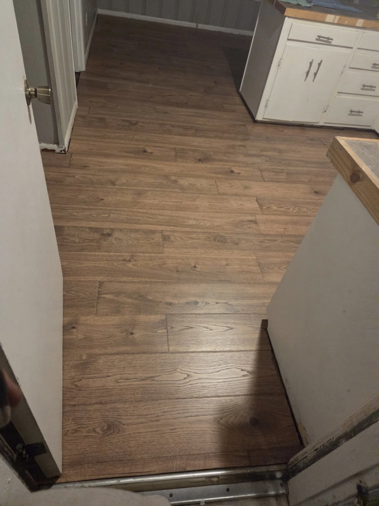 Newly installed wood-look laminate flooring in a home, completed by Joel's flooring & Handyman services in Roy, UT.