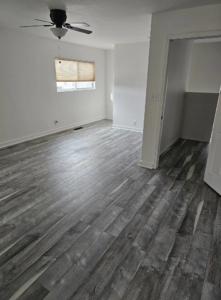Newly installed grey wood-look flooring and a ceiling fan in a renovated room by AV Handyman Services in Rio Rancho, NM.