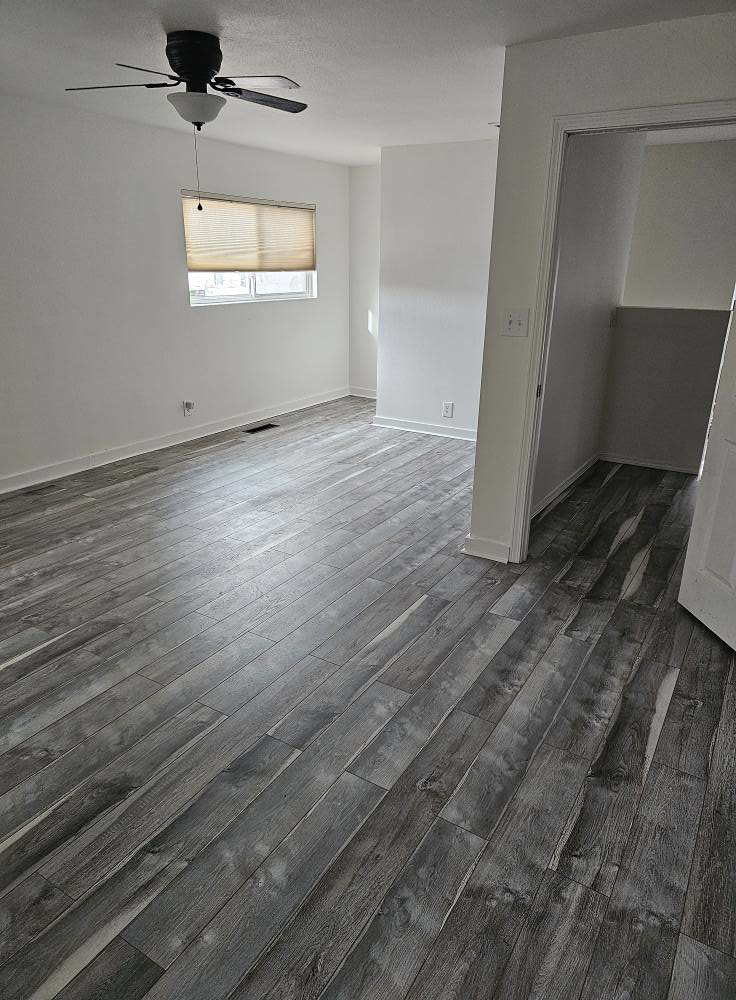 Newly installed grey wood-look flooring and a ceiling fan in a renovated room by AV Handyman Services in Rio Rancho, NM.