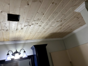 A newly installed wood plank ceiling with crown molding and a light fixture by Verkler Development LLC in Lake Charles, LA.