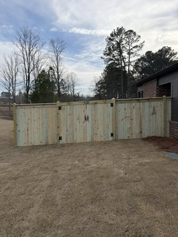 A newly installed wooden privacy fence with a gate by Swift Fencing Co. in Birmingham, AL.