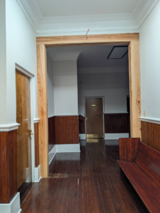 A newly installed raw wooden archway and door frame in a hallway by Bourque's Quality Construction, LLC in Lafayette, LA.