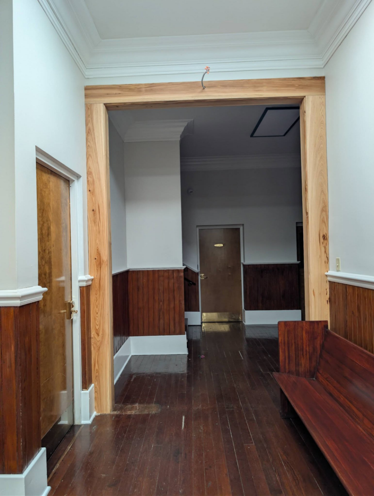 A newly installed raw wooden archway and door frame in a hallway by Bourque's Quality Construction, LLC in Lafayette, LA.