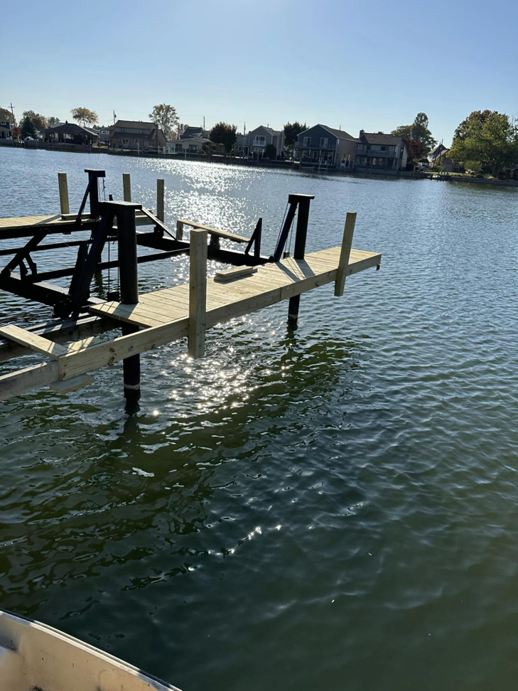 A newly installed wooden dock and boat lift viewed from the water by TopNotch Remodeling & Restoration Service LLC in Warren, MI