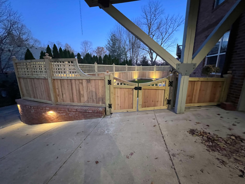 A newly installed wooden fence and gate with outdoor lighting by Capybara Construction in Louisville, KY.